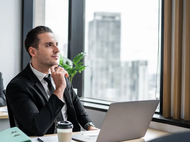 Homme d’affaires qui réfléchit au budget de son site web devant son ordinateur portable
